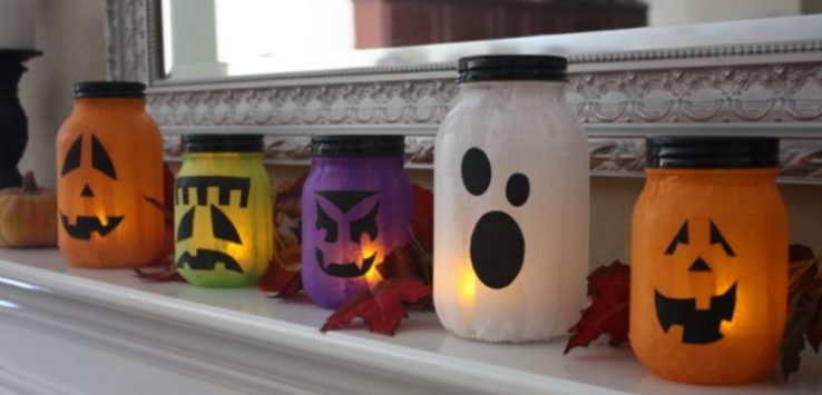 Five different shapes and colors of Jack O’Lanterns mason jar on a mantel.