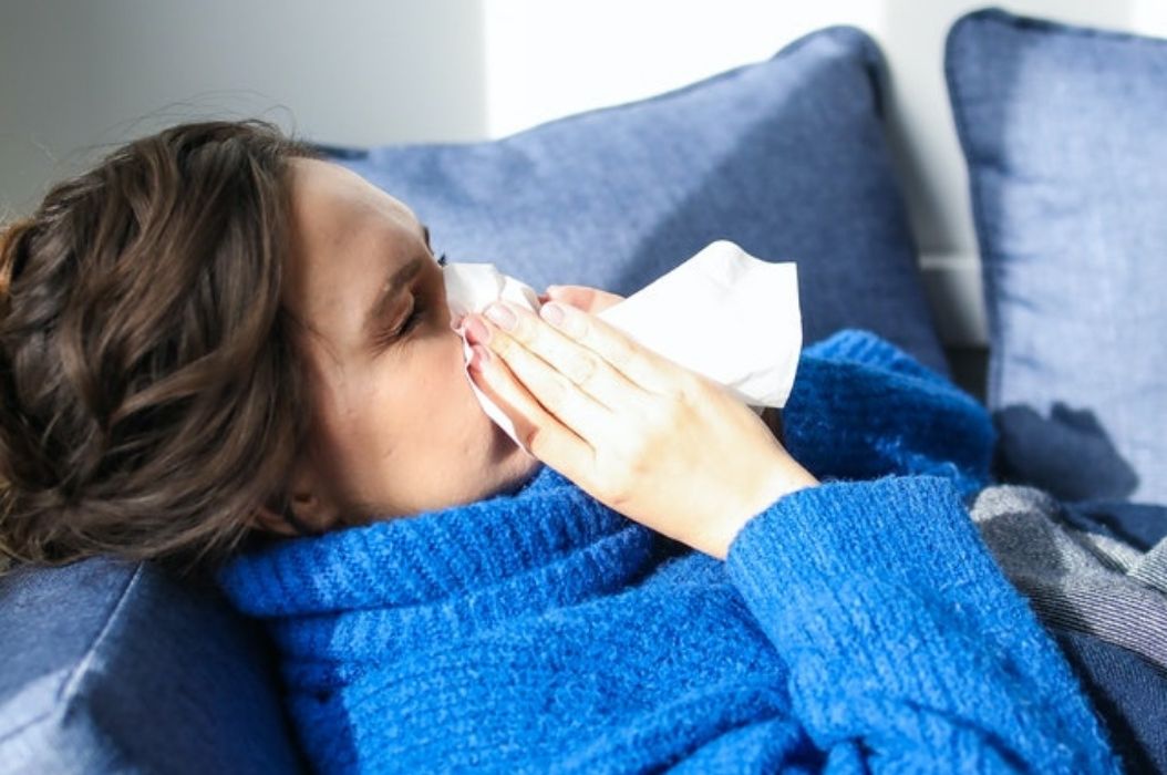 Woman in a blue sweater lying on bed