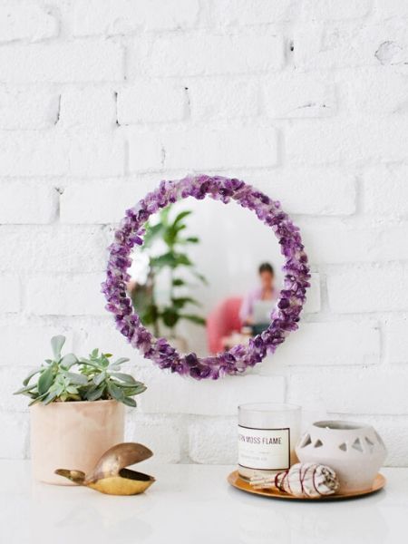 mirror hanging on a wall with purple flower around it