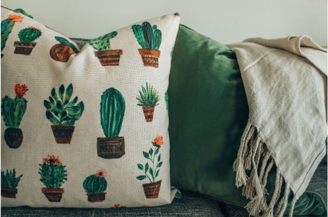 Two cushions with green and grey colors and a grey linen on top of the green cushion