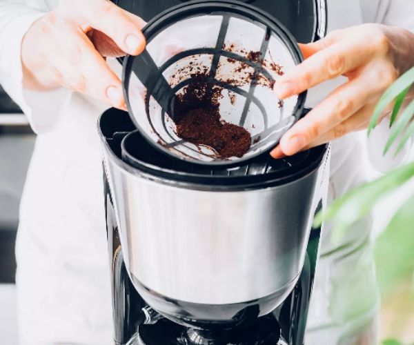 Someone opening the filter of the coffee maker.