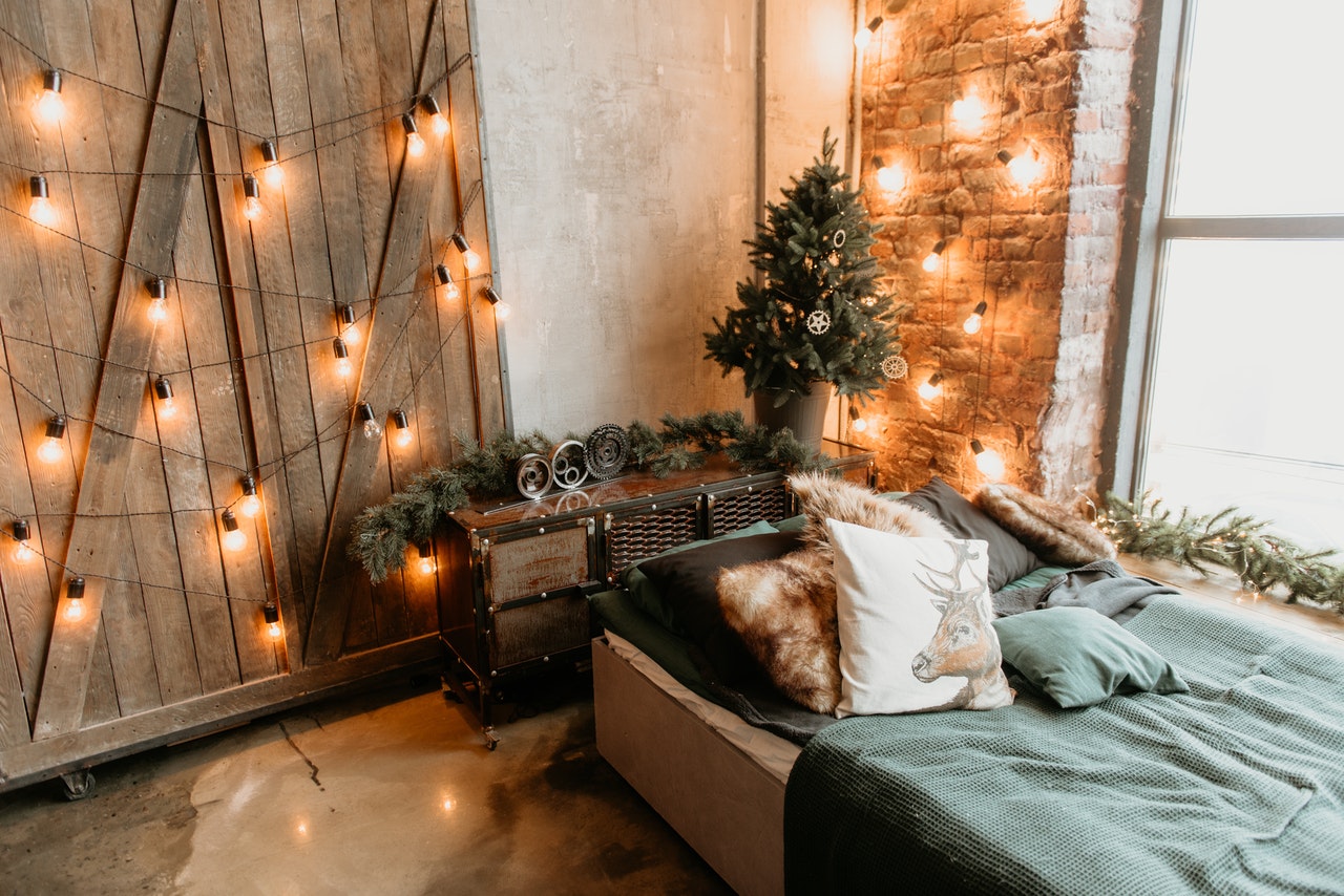 A room filled with lamps decoration on a wall, small pine tree decoration and a bed