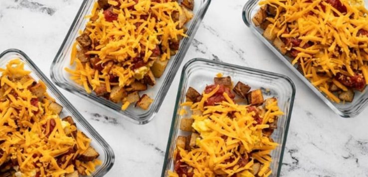 Four meal prep containers filled with roasted potato, scrambled egg, and cheddar cheese.