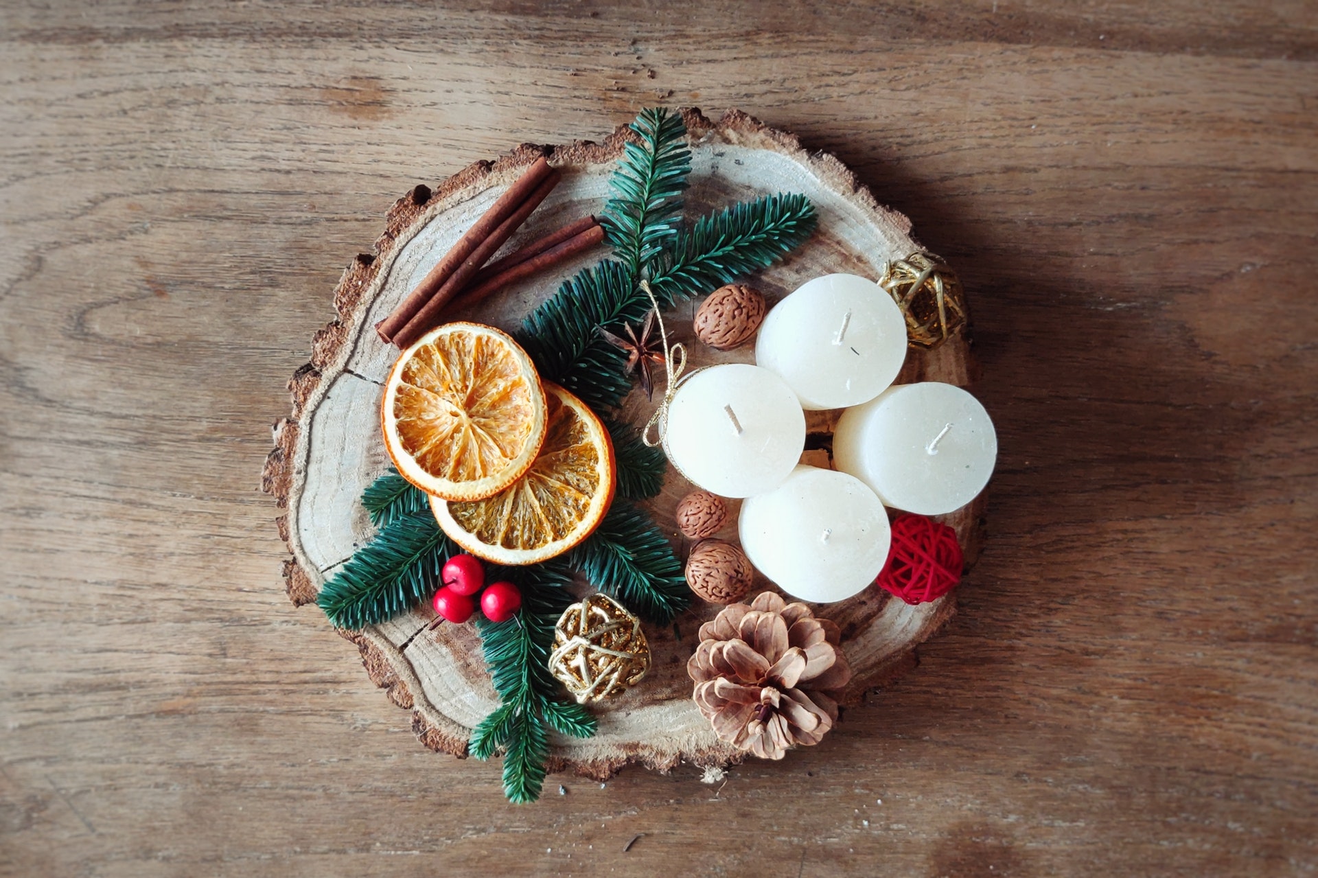 candles, orange skin and pines on top of wood plate